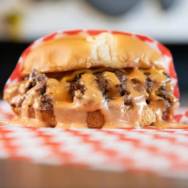 A SMA5H burger with two patties, melted cheese, and special sauce on a red and white checkered wrapper.