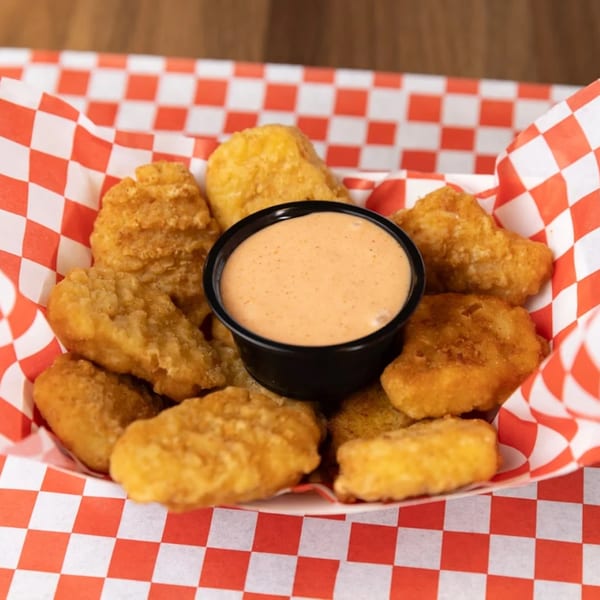 Golden-brown SMA5H chicken nuggets and dipping sauce in a red and white checkered paper tray.