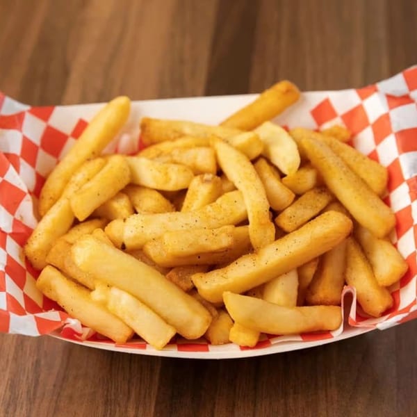 Golden SMA5H fries, seasoned with pepper, in a red and white checkered paper tray.
